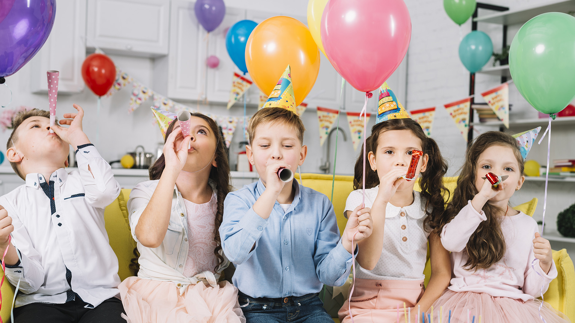 Niños celebrando en una fiesta escolar con globos, ideal para la distribución de regalos promocionales educativos y baratos.